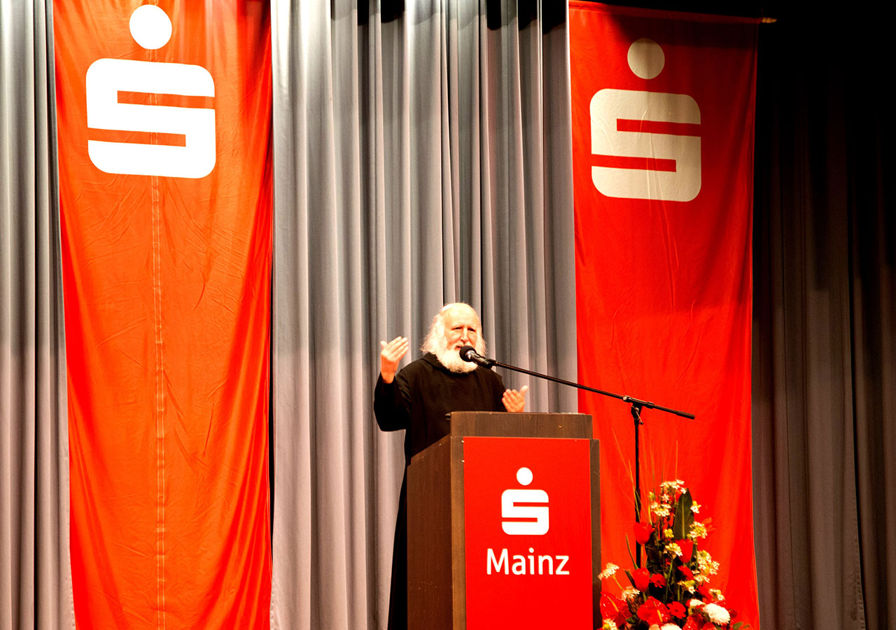 Pater Anselm Grün referiert am Rednerpult vor Kunden der Sparkasse Mainz
