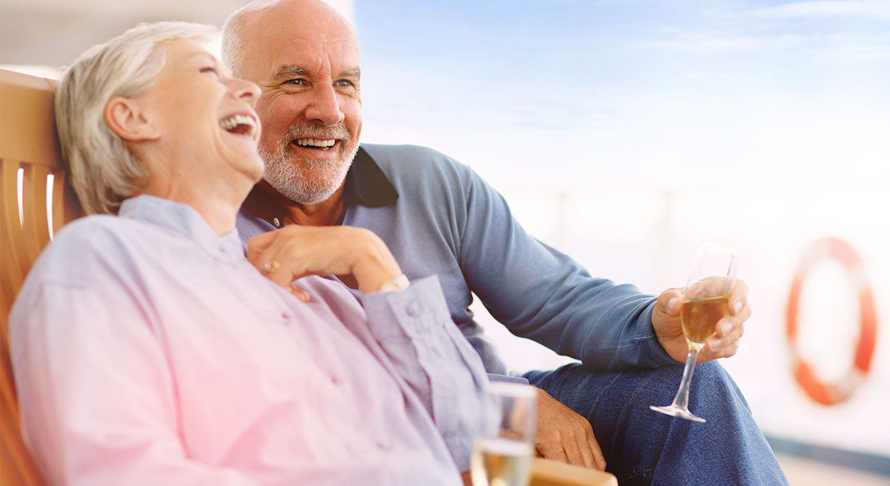 älteres Ehepaar trinkt Sekt, lacht und genießt die gute Altersvorsorge