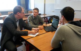 Bastian Winkelhaus von der Sparkasse Mainz sitzt mit Teilnehmern des Deutschen Gründerpreises der Steinhöfelschule Mainz zusammen