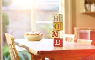 Würfel mit Buchstaben "Home" auf einem Esstisch
