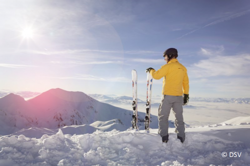 Mann steht neben Skiern im Schnee