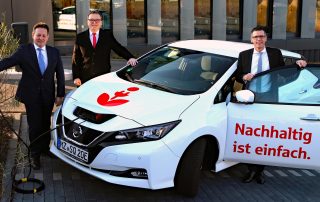 Michael Weil und Thorsten Mühl mit Wolf-Rüdiger Stahl vor dem neuen Elektroauto der Sparkasse Mainz