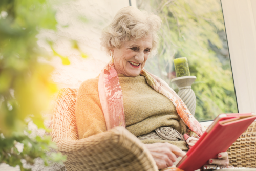 ältere Dame schaut fröhlich auf ihr Tablet