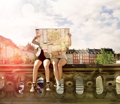 Jugendliche sitzen auf einer Mauer und lesen einen Stadtplan