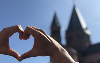 Hände formen ein Herz vor dem Mainzer Dom