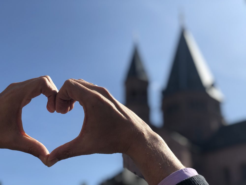 Hände formen ein Herz vor dem Mainzer Dom