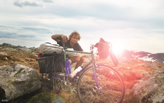 Urlauber mit Fahrrad pausiert auf einem Berg