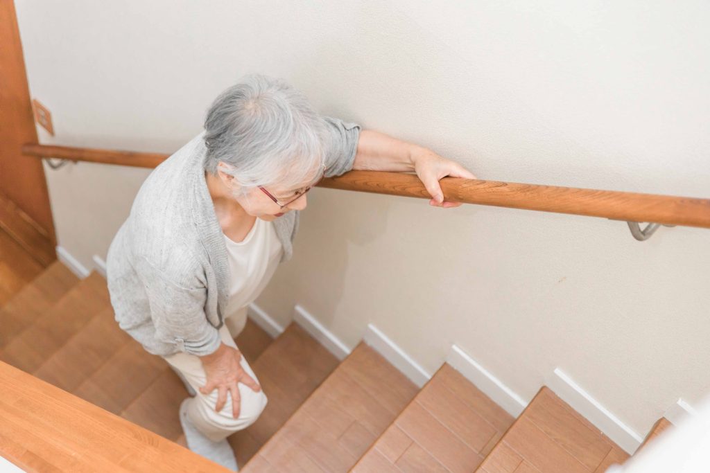 Ältere Frau, die sich am Geländer festhält und eine Treppe hinuntergeht