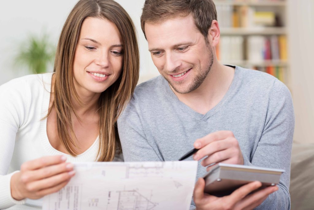 Junges Paar kalkuliert die Baukosten einer Immobilie