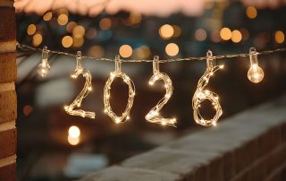 Lichterkette, die die zahl "2026" formt vor einem unscharf aufgenommenen Hintergrund.