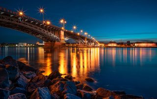 Ufer des Rheins bei Mainz. Zu sehen sind die Theodor-Heuß-Brücke und Mainz bei Nacht.