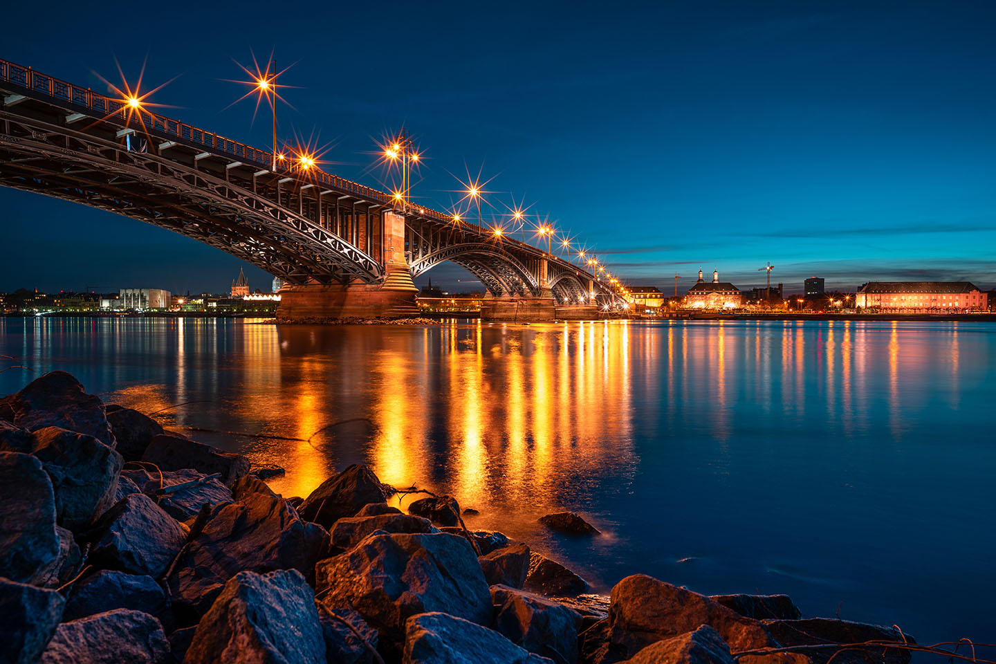 Ufer des Rheins bei Mainz. Zu sehen sind die Theodor-Heuß-Brücke und Mainz bei Nacht.