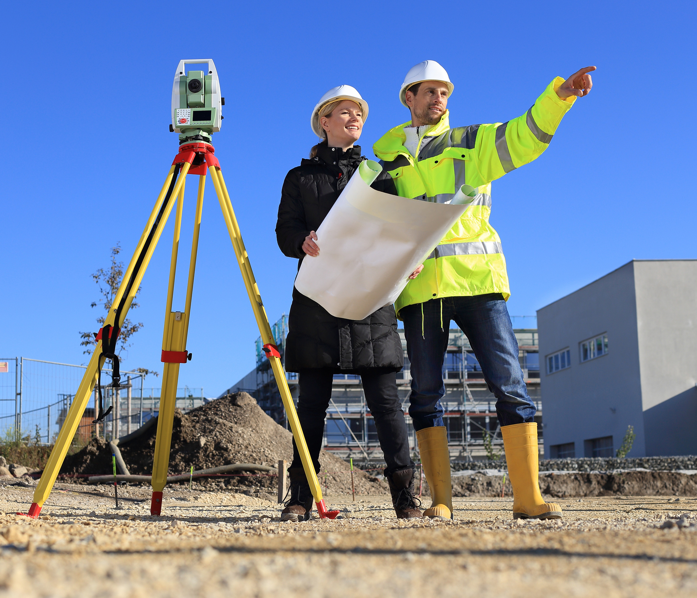 Bauherrin und Bauleiter vermessen einen Bauplatz